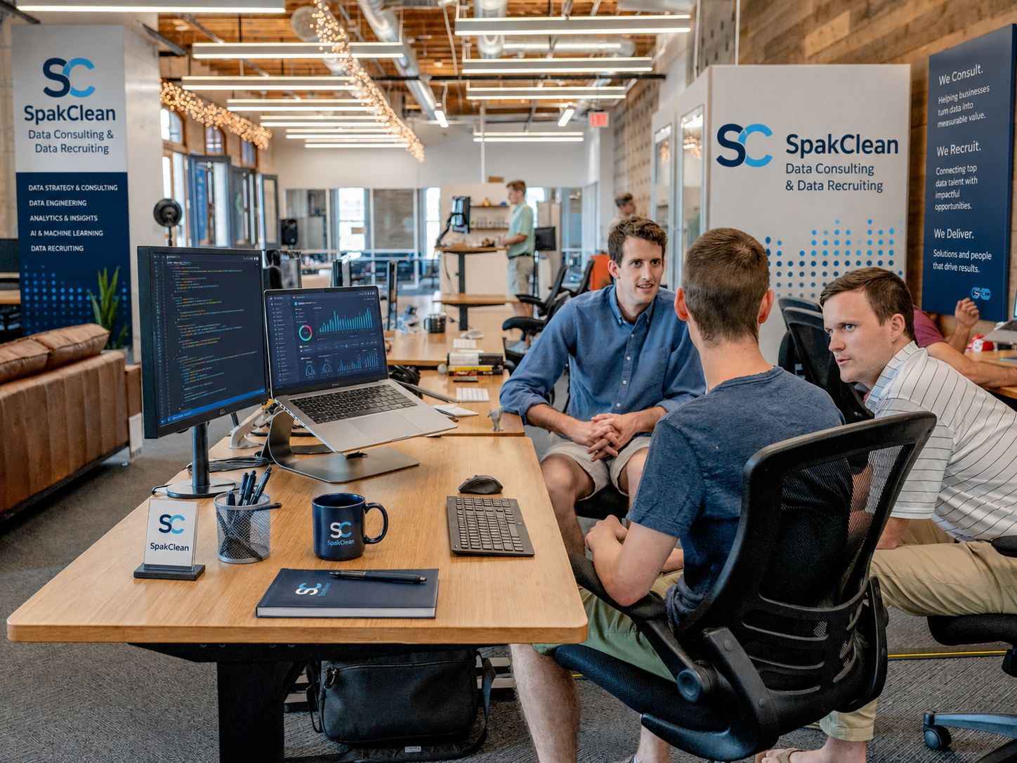 SpakClean data consultants meeting at a workstation with code and analytics dashboards on screen